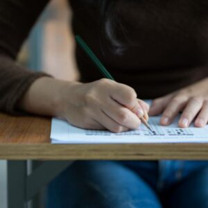 midsection-student-writing-exam-desk-classroom