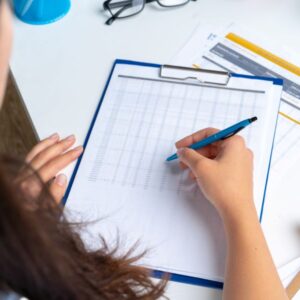 woman-doctor-taking-notes-clipboard-while-sitting-her-table-office