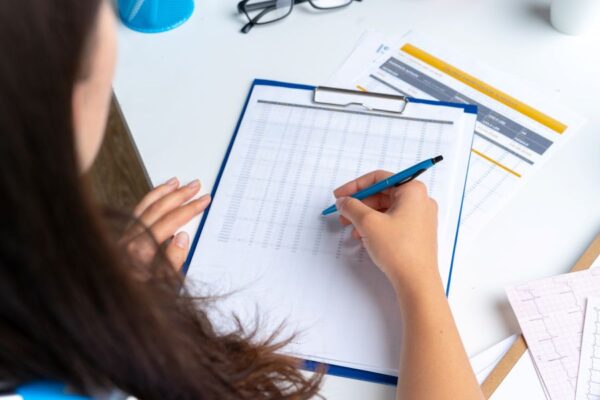 woman-doctor-taking-notes-clipboard-while-sitting-her-table-office